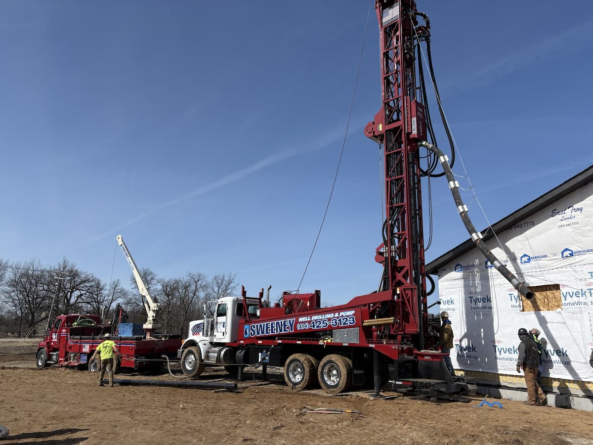 Water well drilling rig operating in a rural field