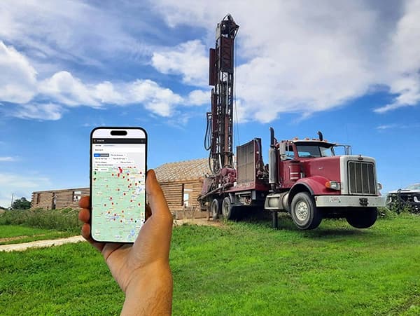 DrillerDB software dashboard showing project management interface on drilling rig background